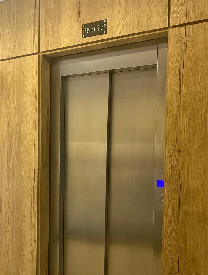 Lobby con boiserie de madera y ascensores de acero instalados por Akon